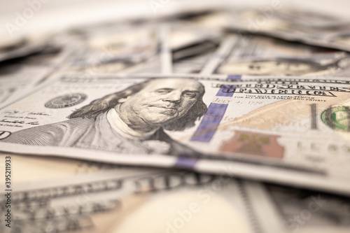 Pile of dollars lies on the table. One hundred dollar bills dumps on table. Background for design from lot of money. Blurred focus. Close-up. Side view
