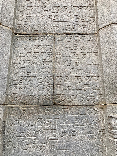 Inscriptions on the ancient temple stone walls. Ancient stone carving. Old stone wall texture. Tamil inscriptions in historical temple walls. Carved inscription in Varadharaja Perumal temple.