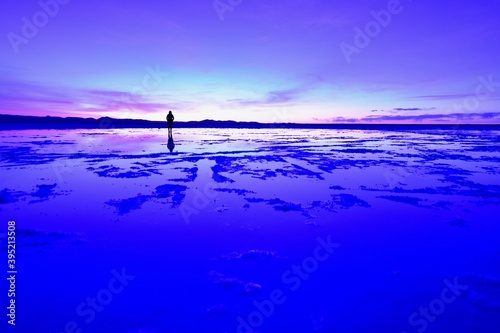 A girl walking further way over the sunrise in Uyuni salt lake

