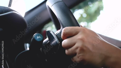 Close-up of a woman holding a steering wheel and pushing a gear shift knob using the Paddle Shift and getting better driving power. Transportation Concept.