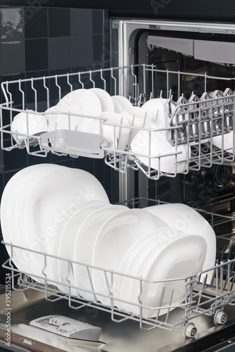 white, clean cups and plates in an open dishwasher
