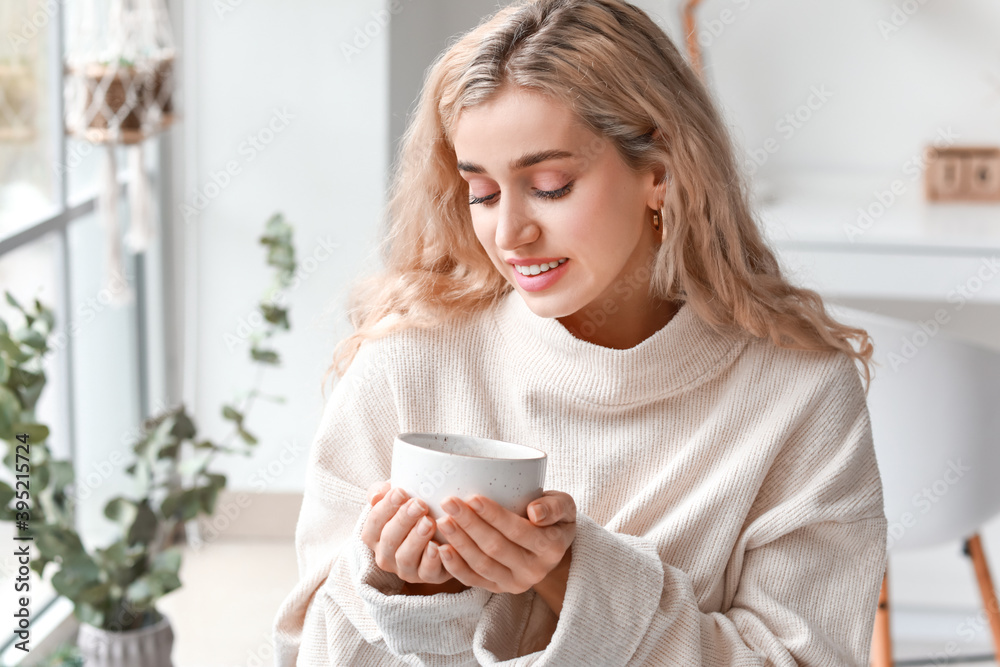 Beautiful young woman in warm clothes drinking tea at home Beautiful young woman in warm clothes drinking tea at home