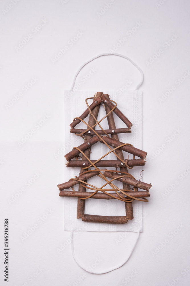 Wooden Christmas tree with a protective white mask on a gray background