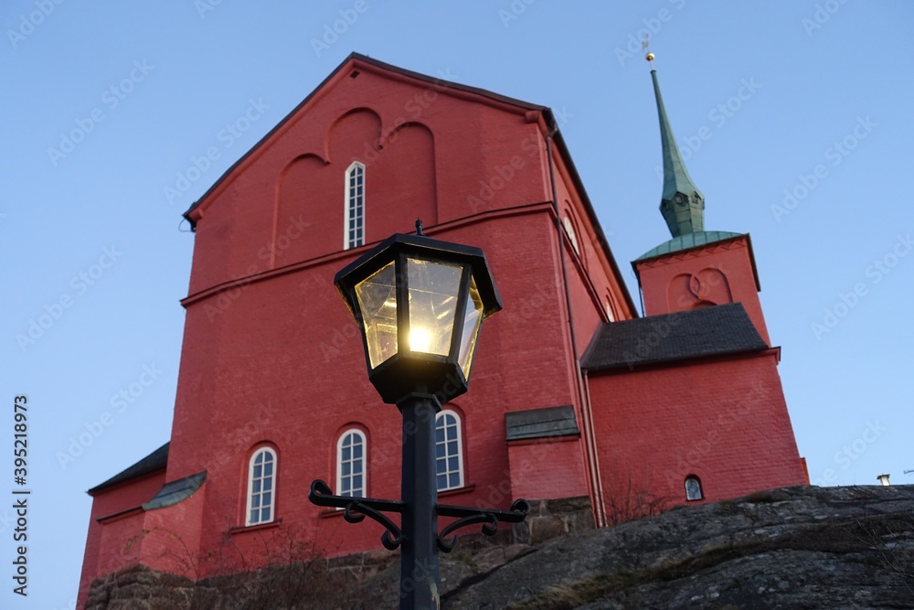 An iron lamppost with a historic red brick church in the background An iron lamppost with a historic red brick church in the background