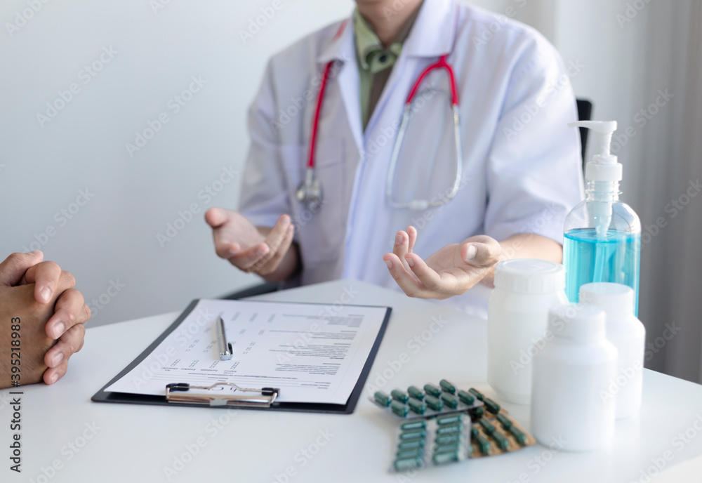 The doctor consults the patient to diagnose the disease and find a cure for symptoms. While writing information and prescriptions in a clinic or hospital office The doctor consults the patient to diagnose the disease and find a cure for symptoms. While writing information and prescriptions in a clinic or hospital office