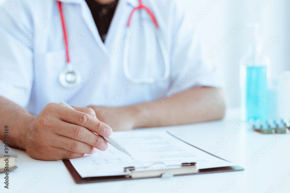 A doctor or nurse who writes medical reports or prescription lists on a clipboard on a hospital desk. A doctor or nurse who writes medical reports or prescription lists on a clipboard on a hospital desk.