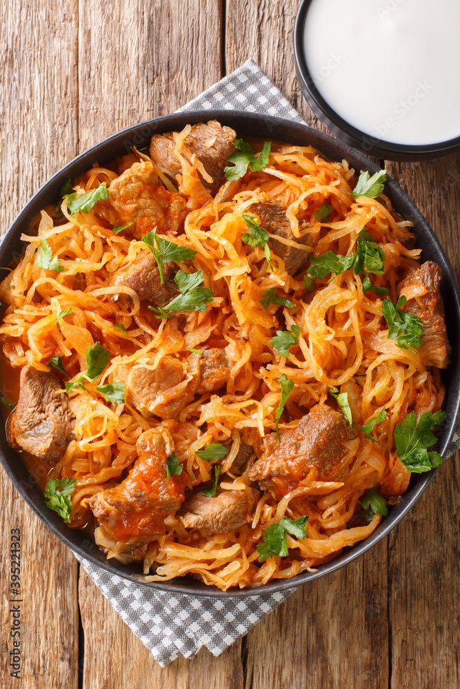Hungarian Szegedin Goulash features slow simmered, succulent pork, onions and sauerkraut in a wonderfully rich paprika infused broth in the plate on the table. Vertical top view from above Hungarian Szegedin Goulash features slow simmered, succulent pork, onions and sauerkraut in a wonderfully rich paprika infused broth in the plate on the table. Vertical top view from above