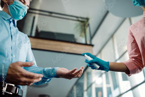 Close-up of business people disinfecting their hands in a hallway during COVID-19 pandemic.