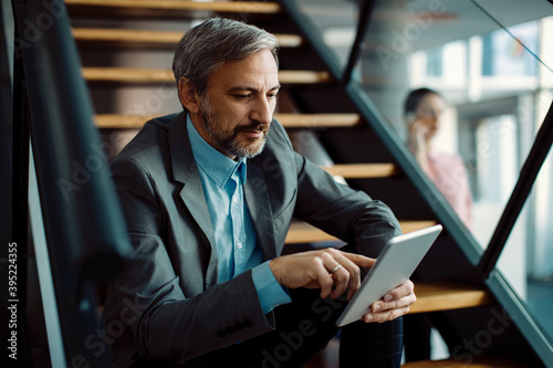 Male entrepreneur using digital tablet while sitting on staircase. © Drazen