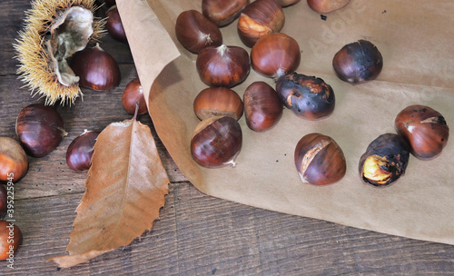 roasted chestnuts  on paper on a paper on a wooden table