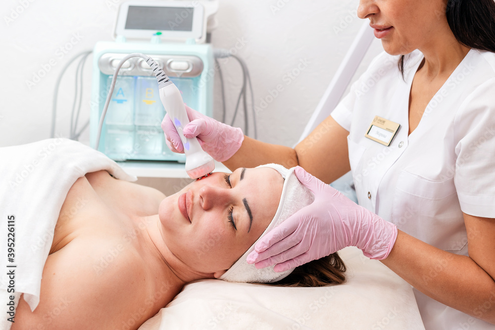 Professional skin care. The cosmetologist makes the RF-lifting procedure for the client. Side view. Copy space. Concept of cosmetology and treatment Professional skin care. The cosmetologist makes the RF-lifting procedure for the client. Side view. Copy space. Concept of cosmetology and treatment