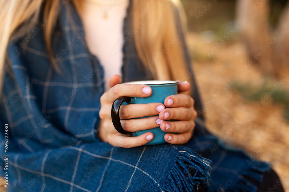 Holding cup of coffe in autumn season, cozy unrecognizable female holding autumn tea, covered with blue plaid. Holding cup of coffe in autumn season, cozy unrecognizable female holding autumn tea, covered with blue plaid.