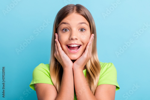 Portrait of young shocked happy amazed positive cheerful girl smiling hold hands cheeks isolated on blue color background