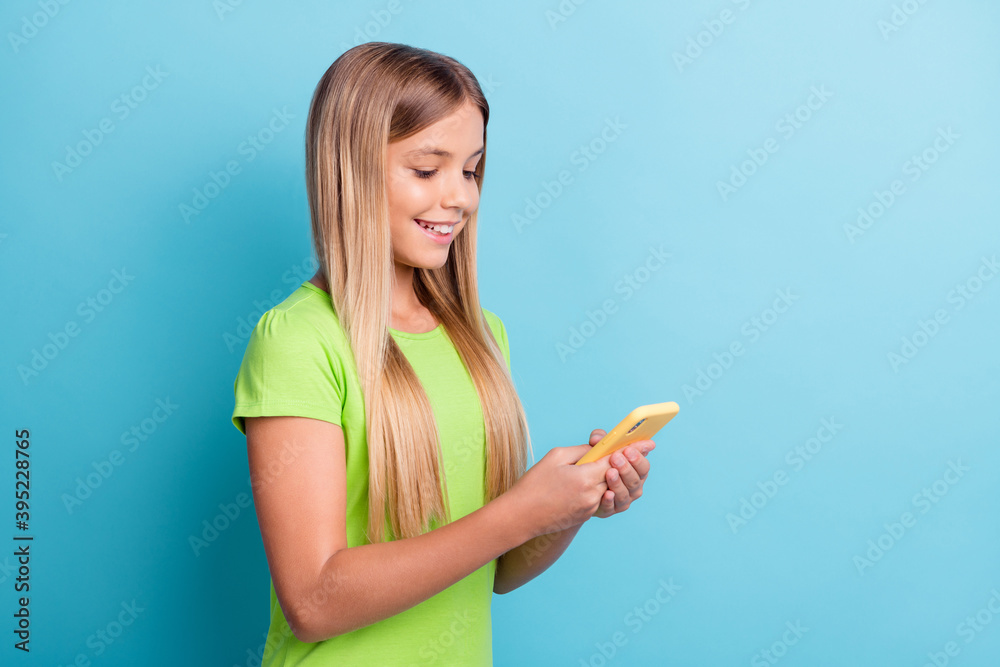 Photo of young happy good mood positive cheerful girl chatting with friends using cellphone isolated on blue color background Photo of young happy good mood positive cheerful girl chatting with friends using cellphone isolated on blue color background