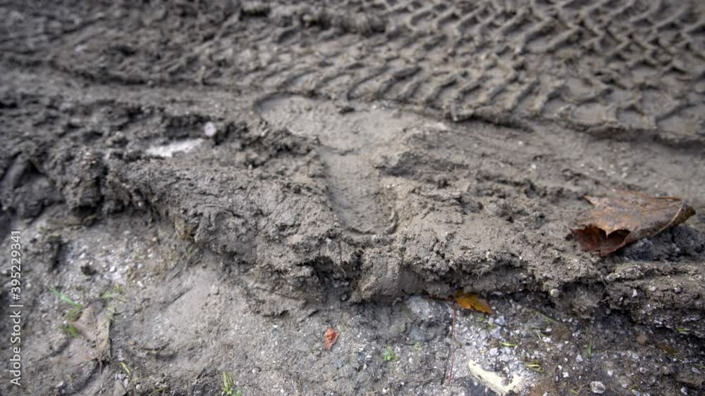 Worker in a working boots steps into the mud and leaves a footprint in mud