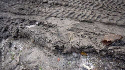Worker in a working boots steps into the mud and leaves a footprint in mud