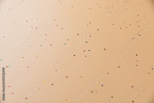 Festive background. Beige background with scattered sparkling colorful confetti. Christmas. Wedding. Birthday. Happy woman's, Mothers, Valentine's Day. Flat lay, top view, copy space..