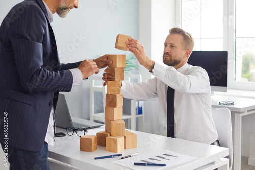 фотографія Father and son building toy block tower on office desk as metaphor of strengthen