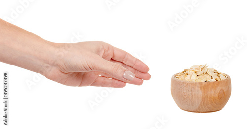 Hand with pumpkin seeds in wooden jar isolated on white background.