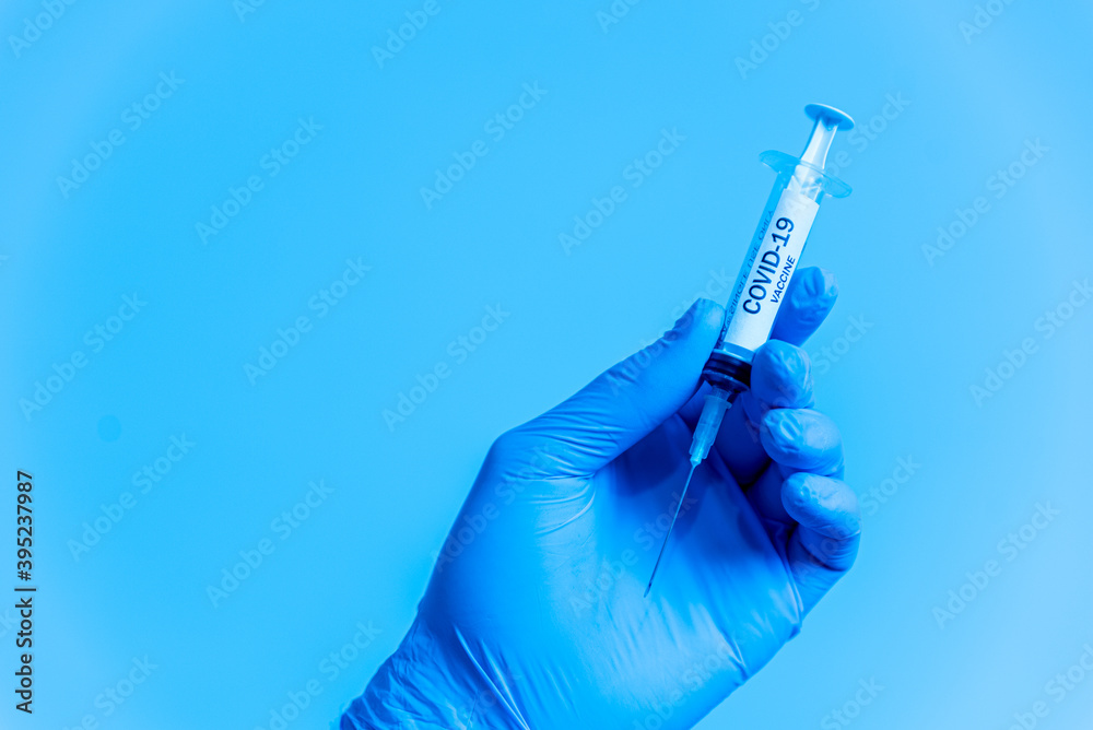 closeup of doctor hand with gloves holding covid-19 vaccine syringe on blue background. concept of science and coronavirus vaccine, healthcare and prevention closeup of doctor hand with gloves holding covid-19 vaccine syringe on blue background. concept of science and coronavirus vaccine, healthcare and prevention