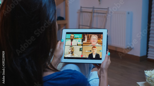 Back view of woman on videocall sitting on comfortable couch. Remote worker having online meeting consulting with colleagues on video conference and webcam chat using internet technology.