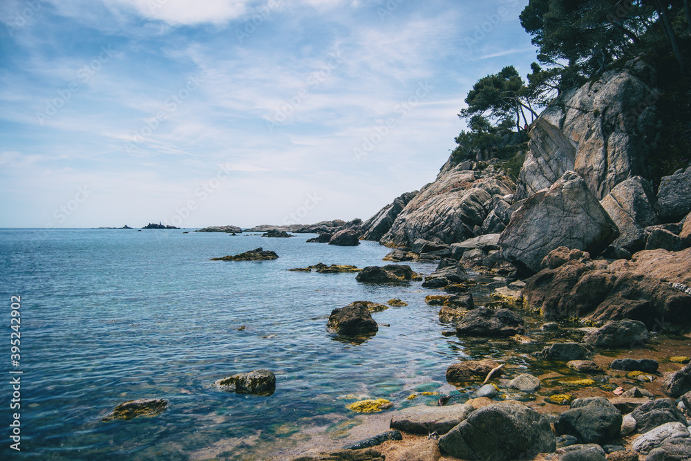 Landscape of a small pebble beach surrounded by rocks with vegetation Landscape of a small pebble beach surrounded by rocks with vegetation