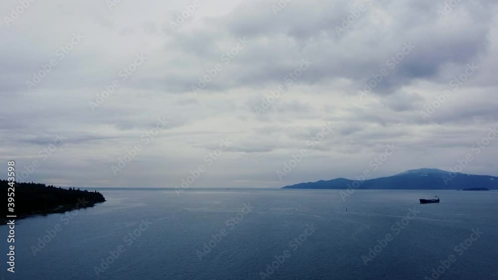 Aerial view of waters and mountains near Vancouver with a beach and cargo ship Aerial view of waters and mountains near Vancouver with a beach and cargo ship