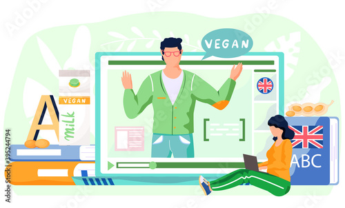 A girl sits on floor near english dictionary with laptop and studies on her computer. Student on online lesson on veganism. Teacher on tablet screen explains new topic about vegan products in english