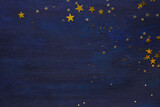 Dark-blue wooden background with golden stars.  Flat lay.