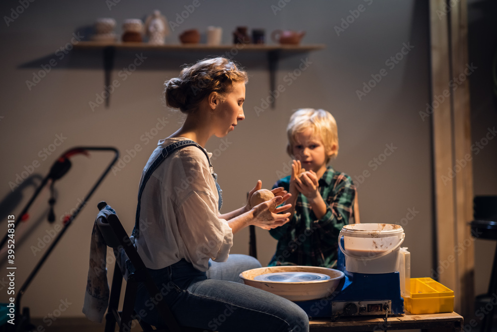 a young mother teaches her son the family pottery craft in a workshop a young mother teaches her son the family pottery craft in a workshop