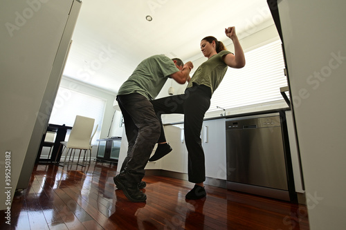 Woman victim using a self defense technique  against a violent man attacker in home kitchen. photo
