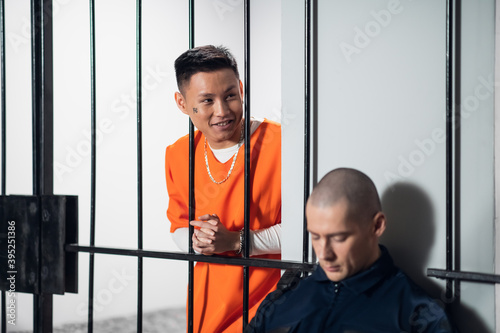 White and asian dangerous criminals and serial killers attack the armed guard who guards their cells. Stretching out his hands to the security guard through the bars