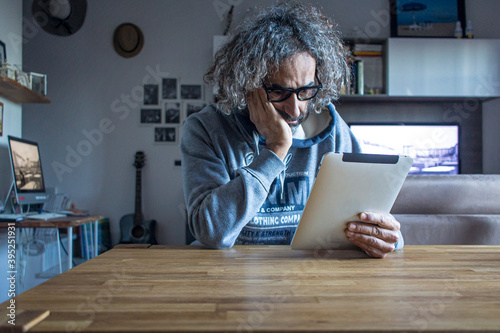 Lockdown e smart working in Italia: un uomo seduto al tavolo di casa legge le notizie quotidiane sul suo tablet