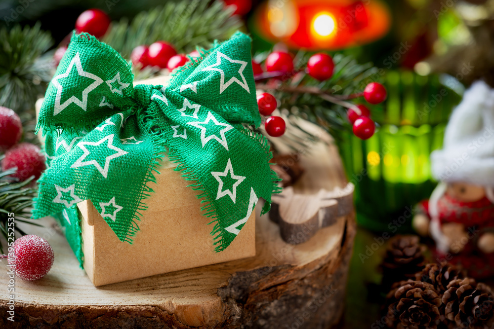 Φωτογραφία Christmas gift box with a beautiful green ribbon tied in a bow with lit candles,