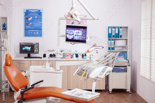 Dental clinic interior with modern dentistry equipment in orange color. Stomatology cabinet with nobody in it and orange equipment for oral treatment. © DC Studio