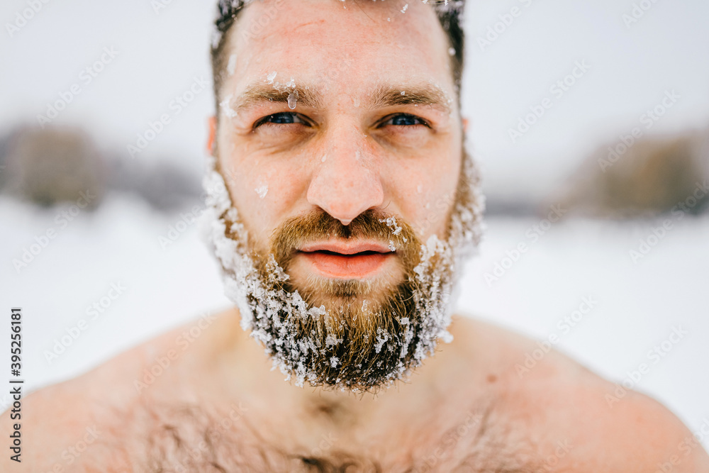 Portrait of strong brutal naked man with frozen beard posing outdoors