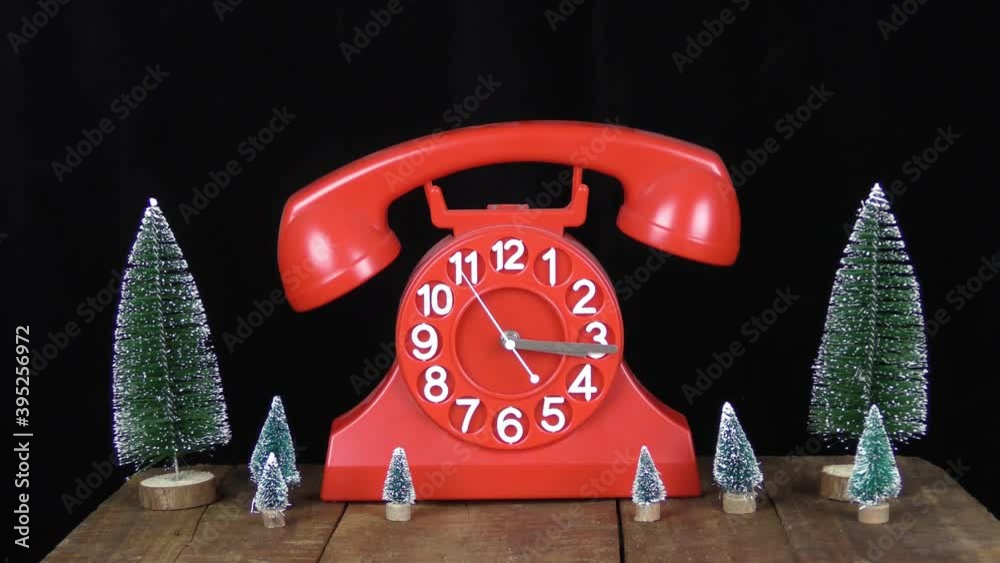telefono orologio rosso con dondolio della cornetta ed alberi di natale