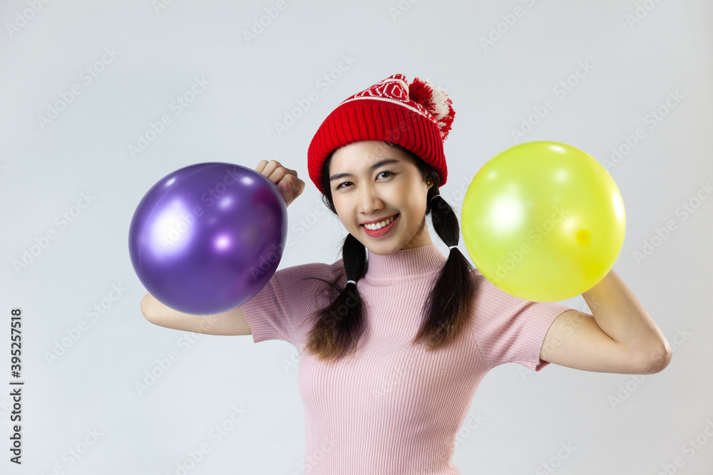 Portrait of young asia woman wearing a red wool hat. Holding a balloon and smiling on white blackground Portrait of young asia woman wearing a red wool hat. Holding a balloon and smiling on white blackground