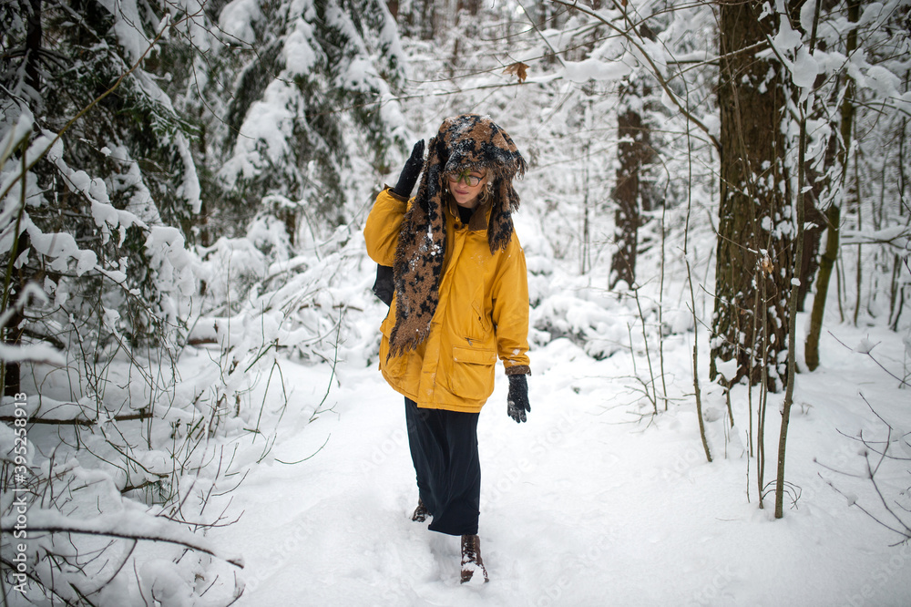 Funny strange young hipster girl with glasses and the scarf covering the head walking in the snow forest Funny strange young hipster girl with glasses and the scarf covering the head walking in the snow forest