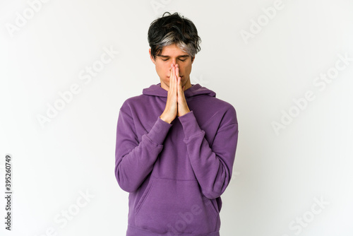 Young skinny hispanic man praying, showing devotion, religious person looking for divine inspiration.
