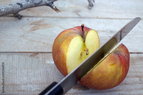 
red apple cut in half on a wooden table with a knife
