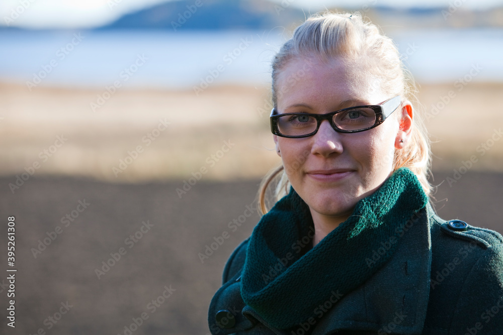 Blonde girl wearing black glasses enjoys a sunny day outside. Looking in camera. Blonde girl wearing black glasses enjoys a sunny day outside. Looking in camera.