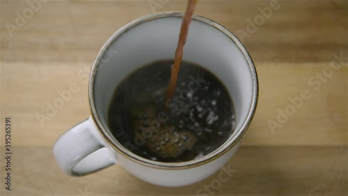 150fps SLOW MOTION WIDE black coffee pours into a cup, splashing photo