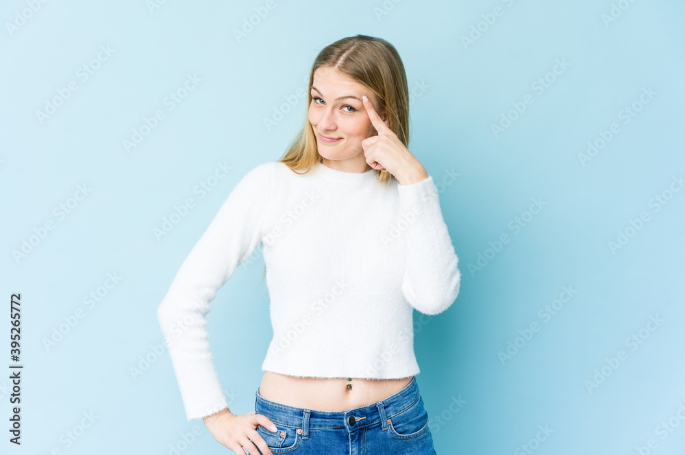 Young blonde woman isolated on blue background pointing temple with finger, thinking, focused on a task. Young blonde woman isolated on blue background pointing temple with finger, thinking, focused on a task.