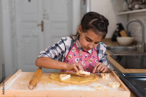 Child prepares cookies and cut out of rolled dough figurines in the shape of a heart. Child's hands making cookies from raw dough in the form of heart, close up.