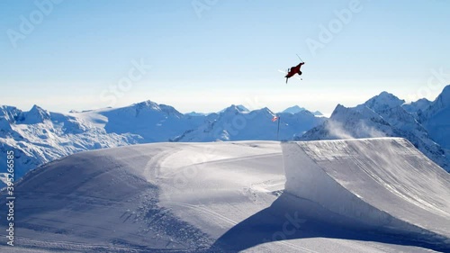 Freestyle skiing in a fun park on a big ski jump. Skiing on a very big jump in ultra slomotion. Freeride skiing awesome ski trick on a big ski jump. Freestyle skier in slomotion. photo