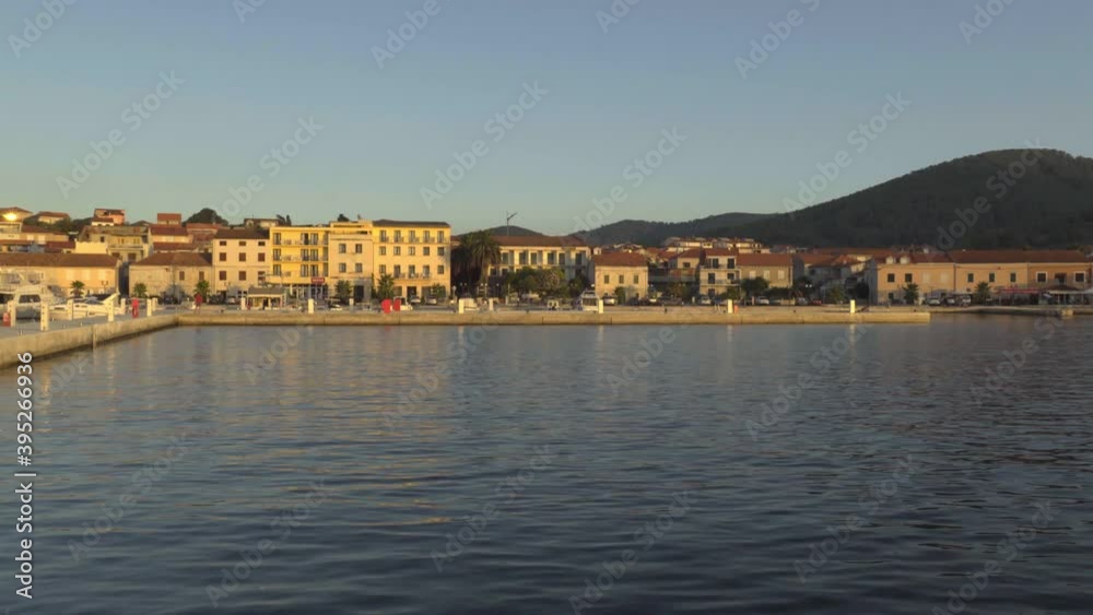 Sunset light hitting the concrete pier and buildings along the shore of Vela Luka in Croatia Sunset light hitting the concrete pier and buildings along the shore of Vela Luka in Croatia