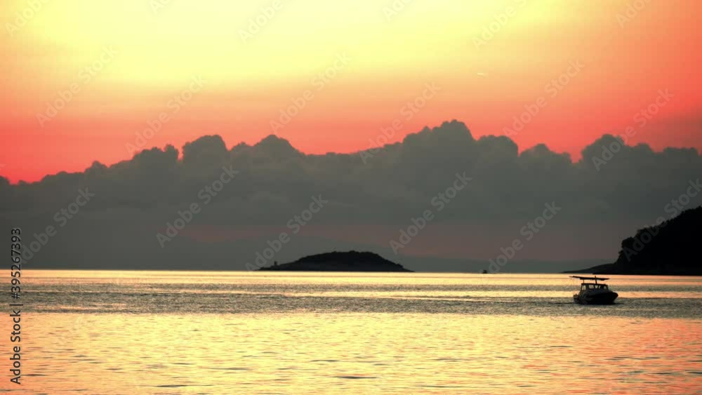 Sunset at Vela Luka, Croatia, with the sun hidden behind clouds casting beautiful colors upwards behind a small island with a lighthouse Sunset at Vela Luka, Croatia, with the sun hidden behind clouds casting beautiful colors upwards behind a small island with a lighthouse