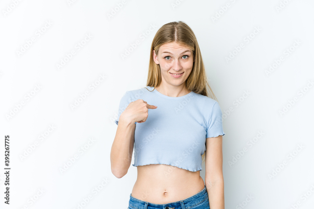 Young blonde woman isolated on white background surprised pointing with finger, smiling broadly. Young blonde woman isolated on white background surprised pointing with finger, smiling broadly.
