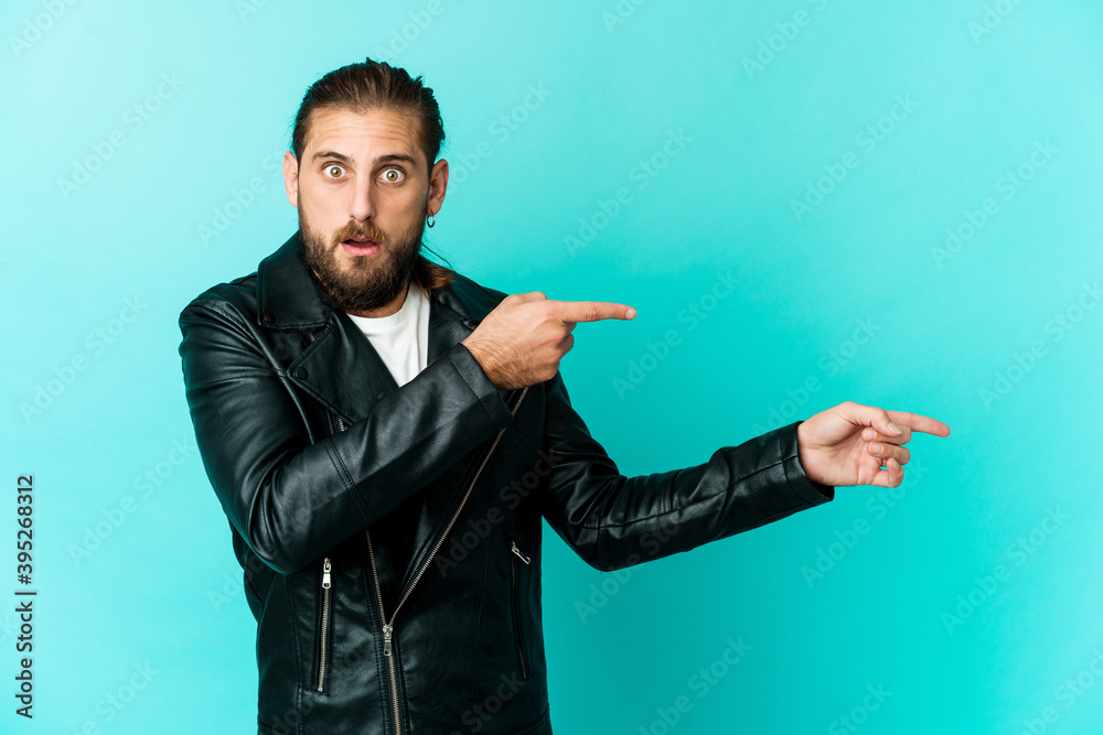 Young man with long hair look pointing with forefingers to a copy space, expressing excitement and desire. Young man with long hair look pointing with forefingers to a copy space, expressing excitement and desire.